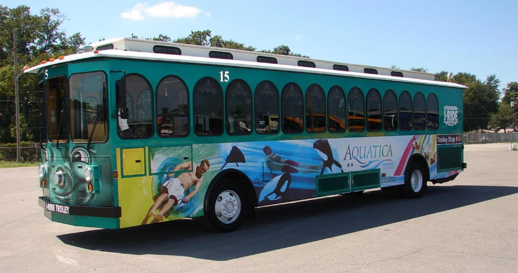 A colorful trolley bus with "Aquatica" branding, featuring images of water sports