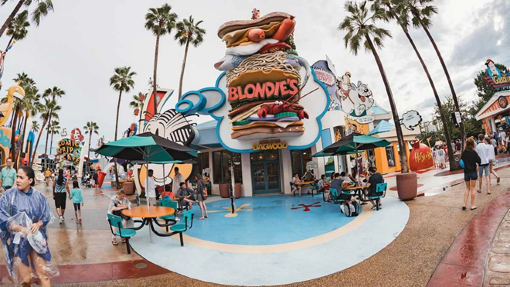 A vibrant theme park eatery named "Blondies" showcases a giant cartoon sandwich