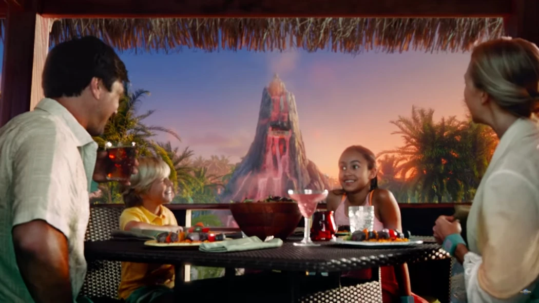Family dining outdoors with volcano and sunset backdrop
