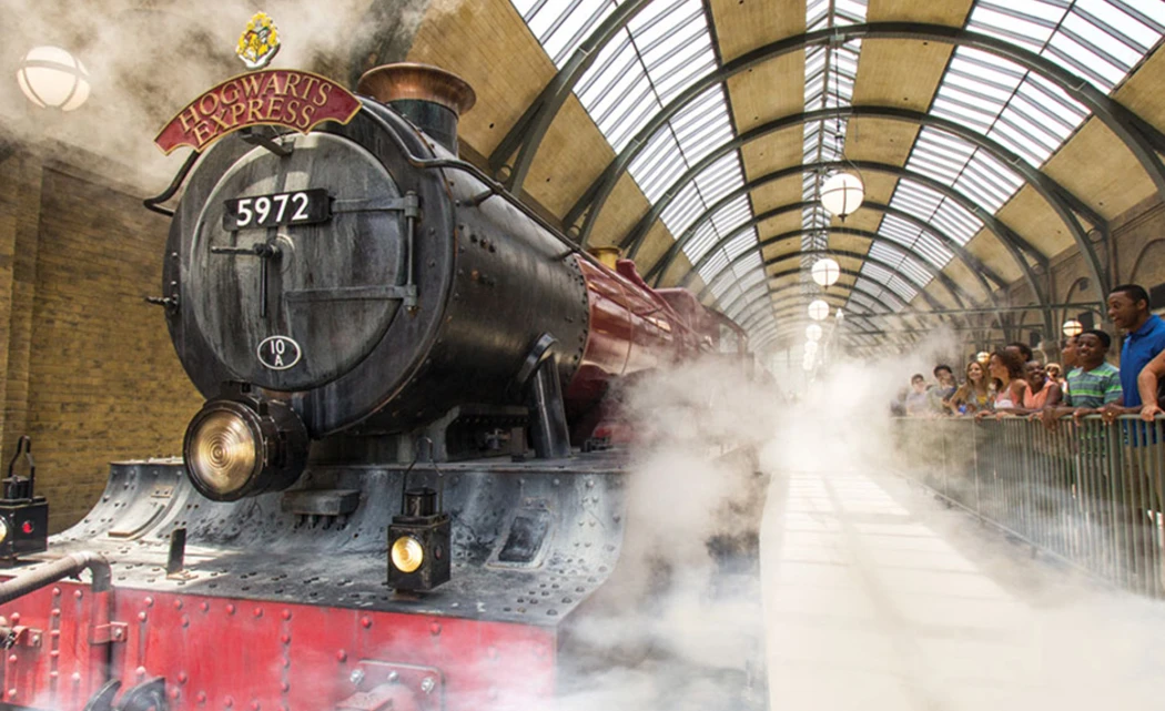The Hogwarts Express steams along a bustling platform filled with excited onlookers
