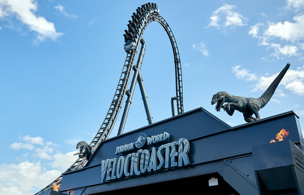 The entrance of Jurassic World VelociCoaster featuring a looping track with raptor sculptures