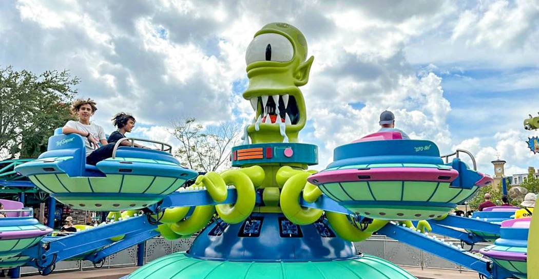 A ride featuring an oversized green alien figure and spinning saucers, with kids enjoying the fun