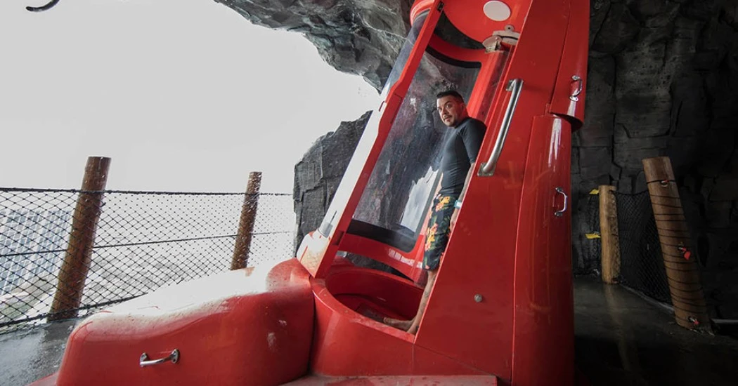 A man inside a red capsule slide with steep vertical drop