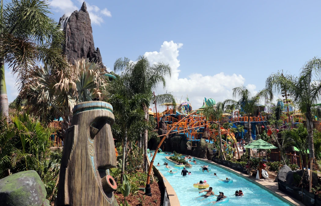 A lazy river, tropical plants, and a towering rock structure in Volcano bay water park