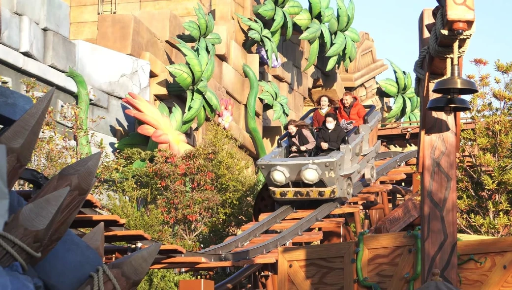 A thrilling roller coaster ride with jungle-themed decorations and lush greenery, showcasing an excited group of riders