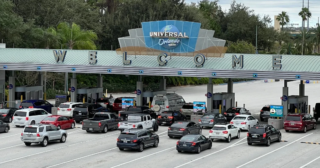 Entrance to Universal Orlando Resort with a "Welcome" sign and cars lined up at the toll booths