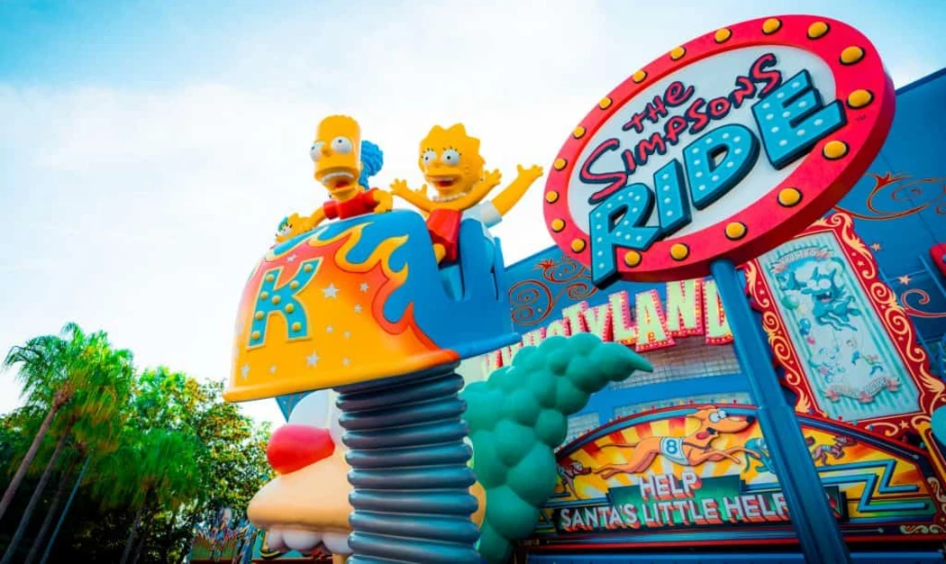 Colorful sign for "The Simpsons Ride" with Bart and Lisa Simpson joyfully perched atop a ride