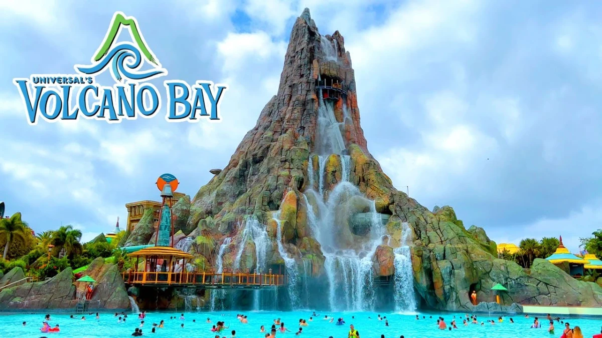 A huge volcano mountain with waterfall and pool around where people are swimming