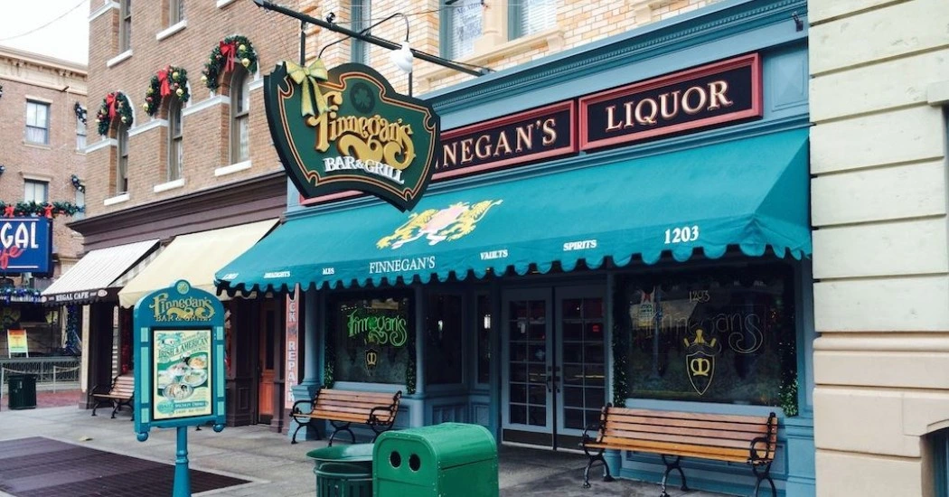 Exterior view of Finnegan's Bar & Grill with festive decorations featuring a green awning and signs for liquor and menu specials