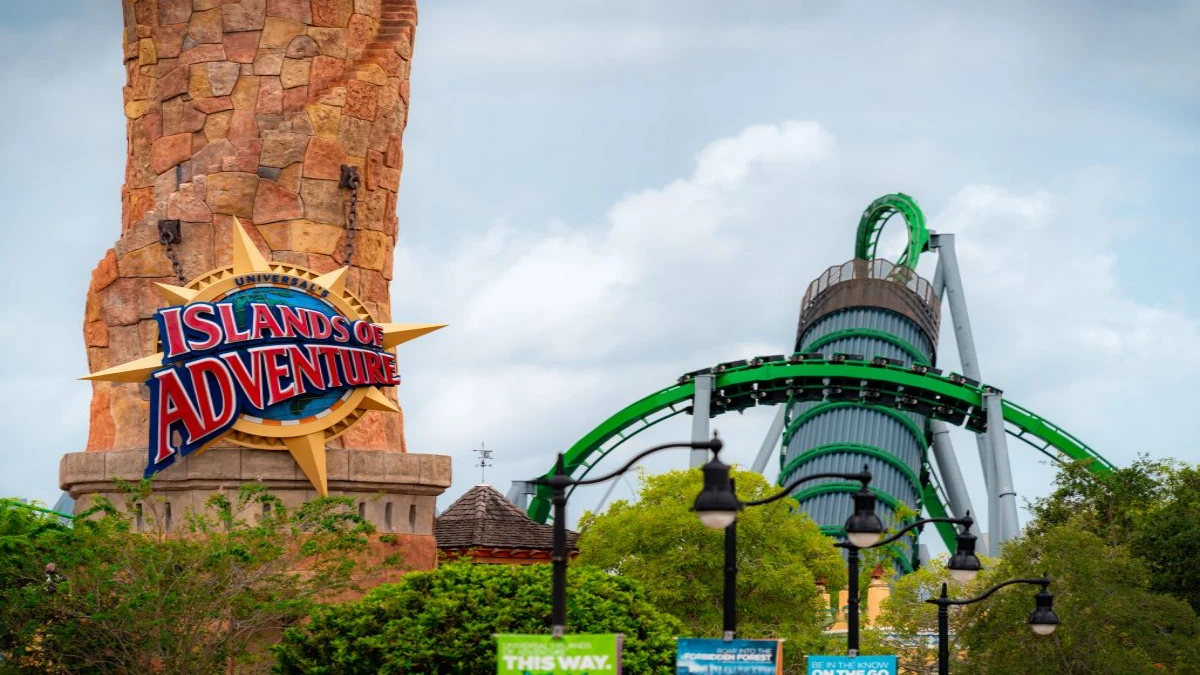 A tower with Islands of Adventure written on it and a rollercoaster nearby
