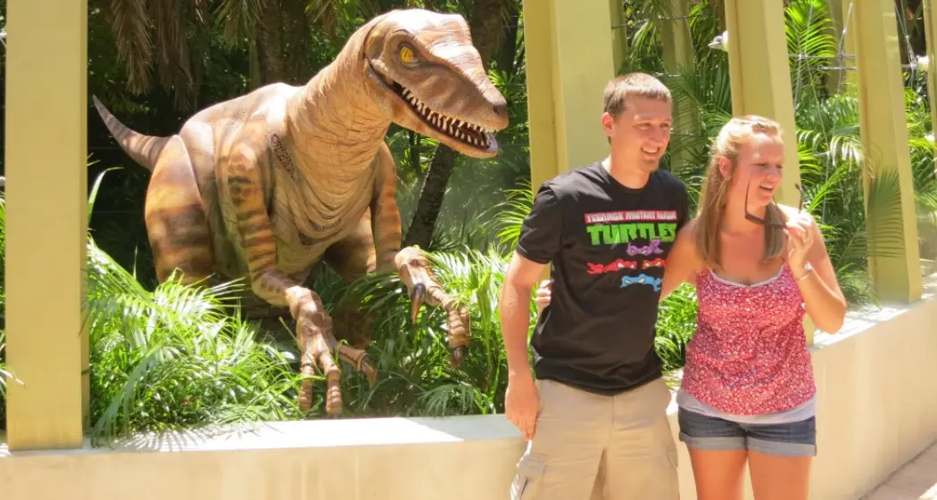 A couple posing in front of a dinosaur